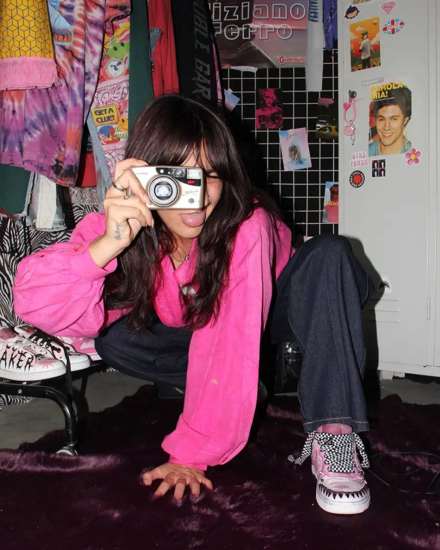 Ragazza con felpa rosa che scatta una foto con fotocamera vintage con scarpe personalizzate YK2 di Seddys, cultura pop anni 2000